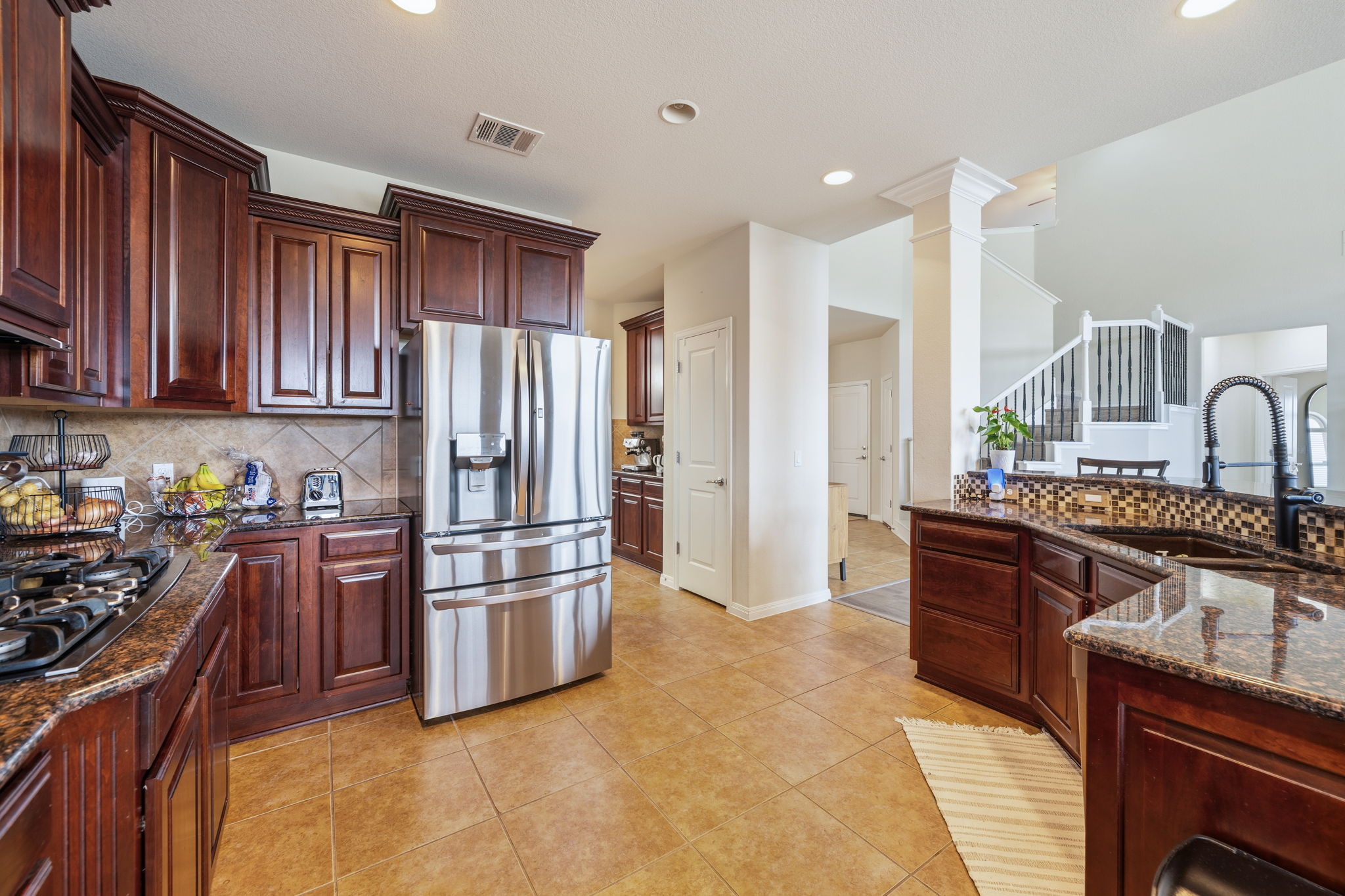 1581 Grassy Field Road Austin, TX 78737 - Photo 12 of 37 Rich wood cabinetry paired with granite countertops anchors this open kitchen design.