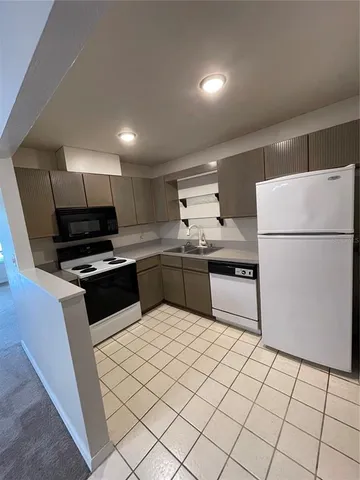 a kitchen with granite countertop a refrigerator a sink and white cabinets