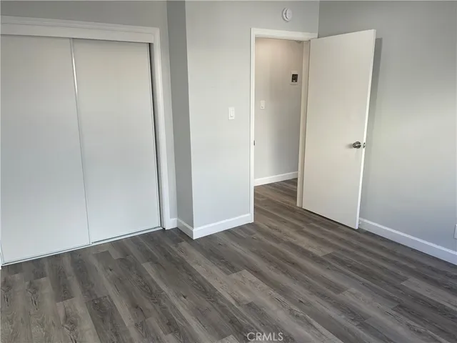 a view of an empty room with closet and wooden floor