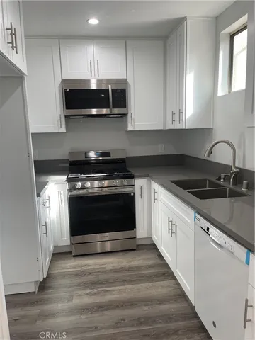 a kitchen with granite countertop a stove top oven a sink and dishwasher a refrigerator with wooden cabinets