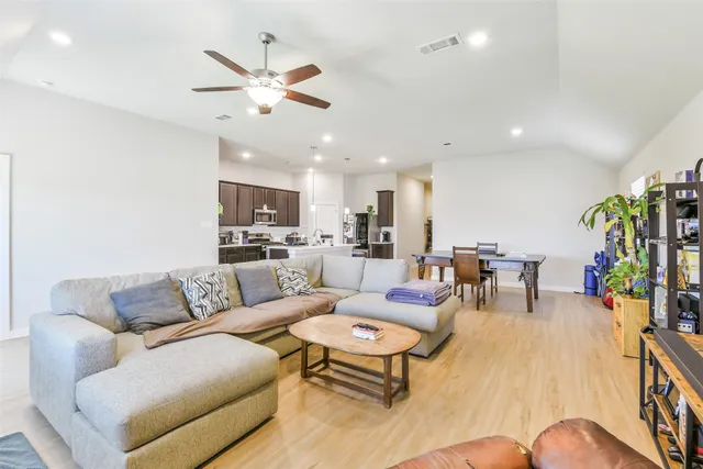 a living room with furniture kitchen view and a chandelier