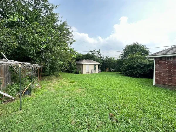 a view of a backyard with table and chairs plants and large tree
