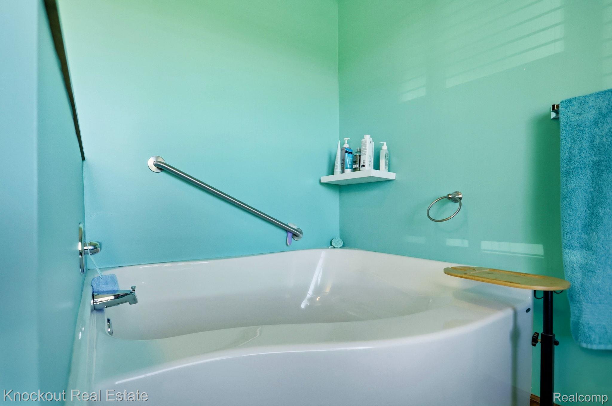 5727 Mackinaw Road Saginaw, MI 48604 - Photo 27 of 60 White soaking tub with chrome fixtures, a corner shelf, and a wall-mounted grab bar