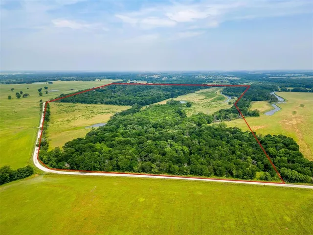 an aerial view of residential houses with outdoor space and trees