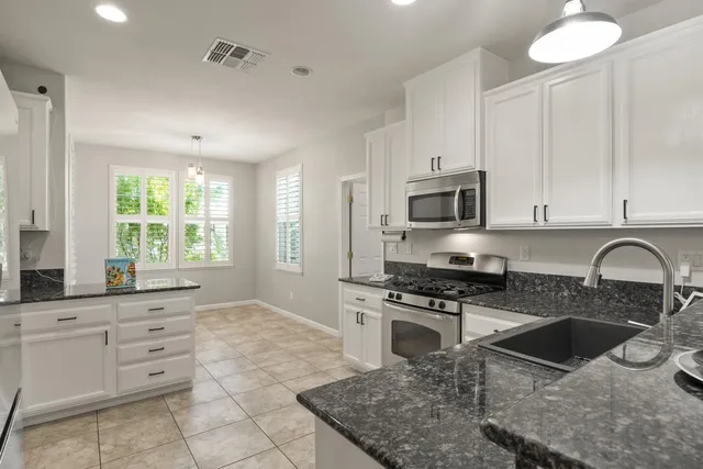 a kitchen with granite countertop a stove a sink and a microwave