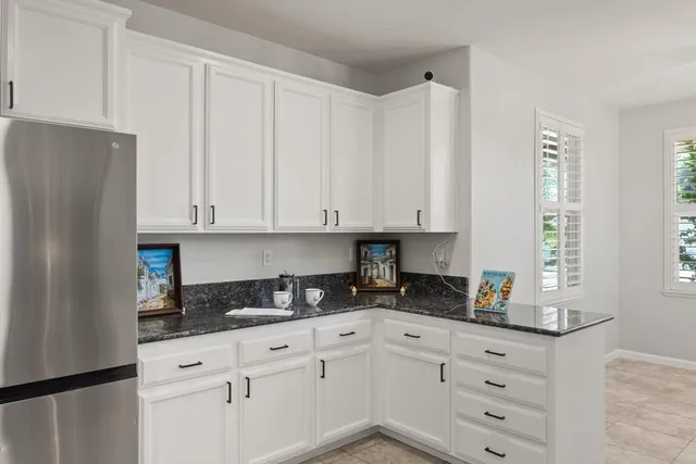 a kitchen with granite countertop white cabinets and stainless steel appliances