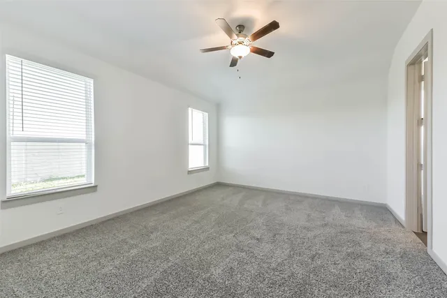 an empty room with windows and fan