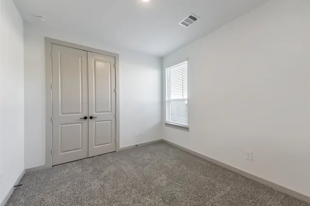 a view of an empty room with closet and a window