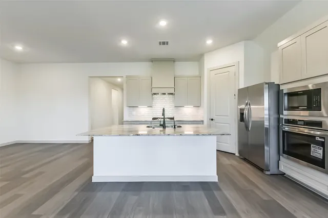 a large kitchen with stainless steel appliances a large counter top a stove and a refrigerator