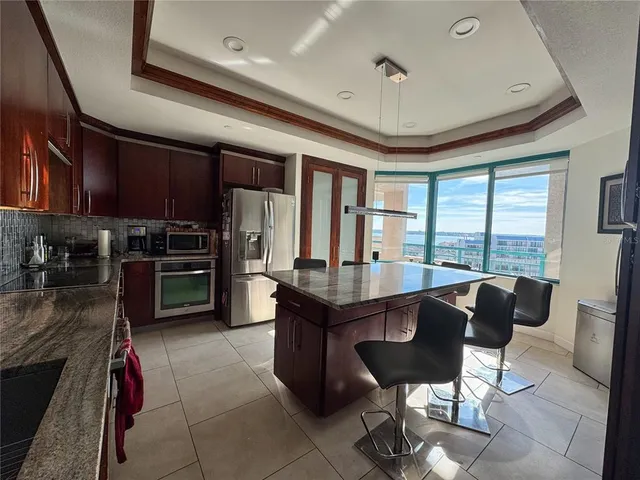 a kitchen with stainless steel appliances granite countertop a stove refrigerator and a dining table with the kitchen view