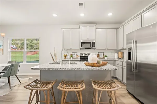 a kitchen with stainless steel appliances granite countertop a stove top oven a sink dishwasher a dining table and chairs