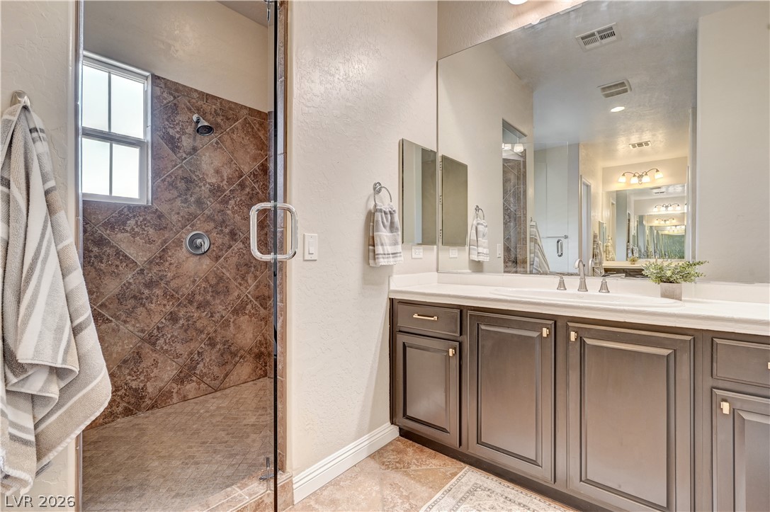 2793 Rosenhearty Drive Henderson, NV 89044 - Photo 40 of 85 This primary bathroom presents a spacious vanity with dual sinks, a large mirror, and a generously sized walk-in shower.