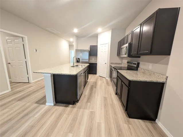a large kitchen with kitchen island granite countertop a sink dishwasher stove and cabinets