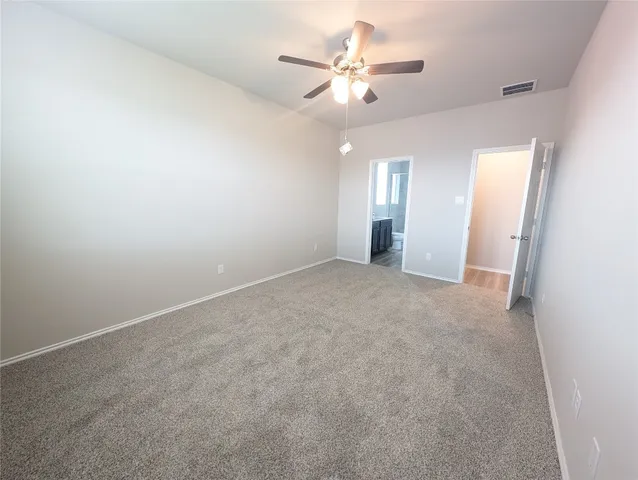an empty room with chandelier fan and windows