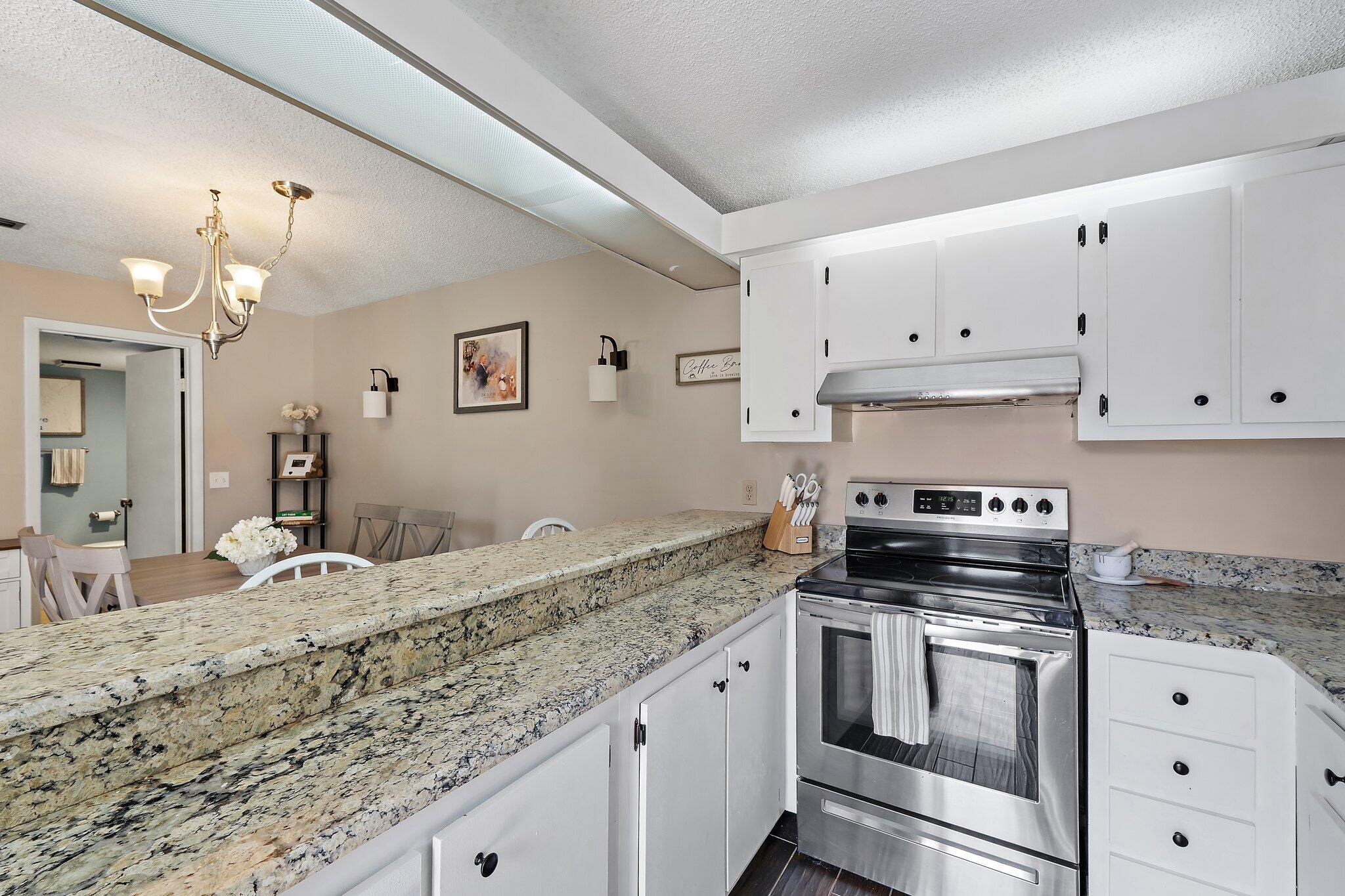 825 Center Street, Unit 30A Jupiter, FL 33458 - Photo 15 of 33 a kitchen with granite countertop a stove sink and cabinets