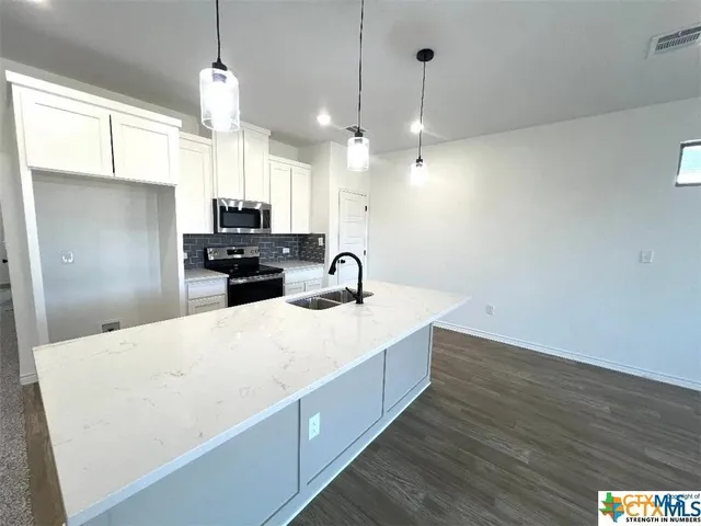 a large kitchen with kitchen island a stove a sink a center island and wooden floor