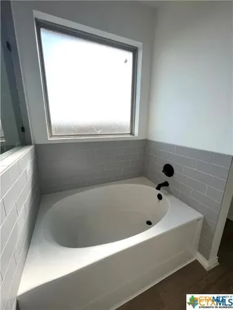 a white bath tub sitting in a bathroom next to a window
