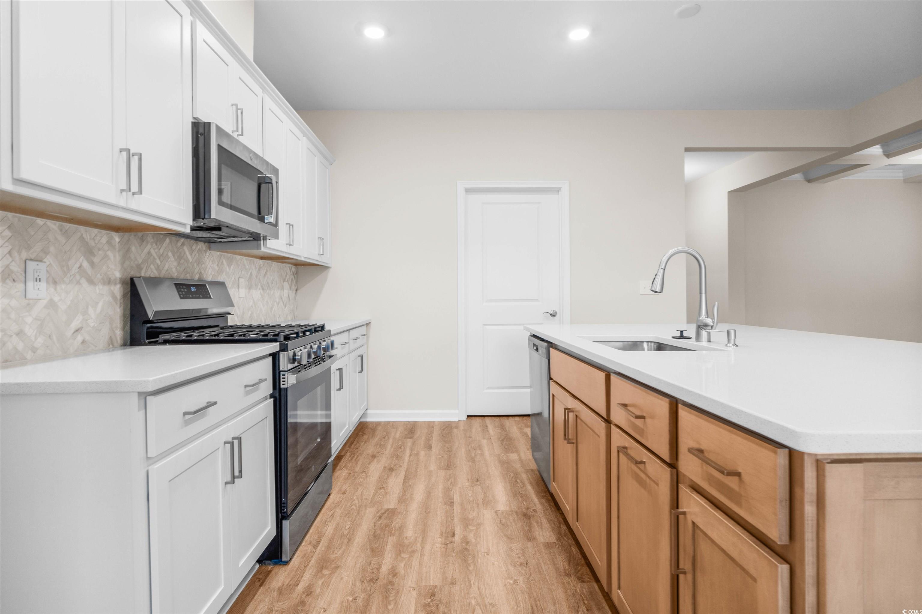 500 Sheepbridge Way Longs, SC 29568 - Photo 3 of 26 Kitchen featuring appliances with stainless steel finishes, white cabinetry, light wood-type flooring, recessed lighting, and backsplash