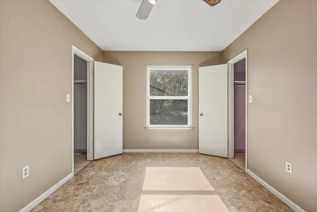 an empty room with closet and windows