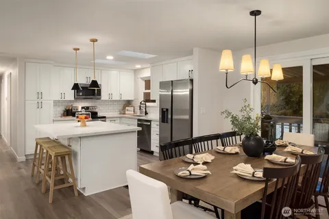 a kitchen with refrigerator a sink dining table and chairs