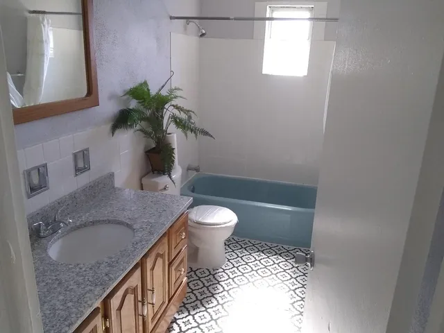 a bathroom with a granite countertop sink a toilet and shower