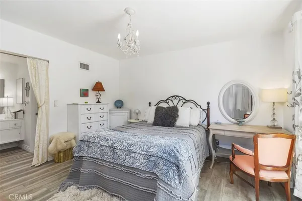 a bedroom with a bed a chandelier and dresser