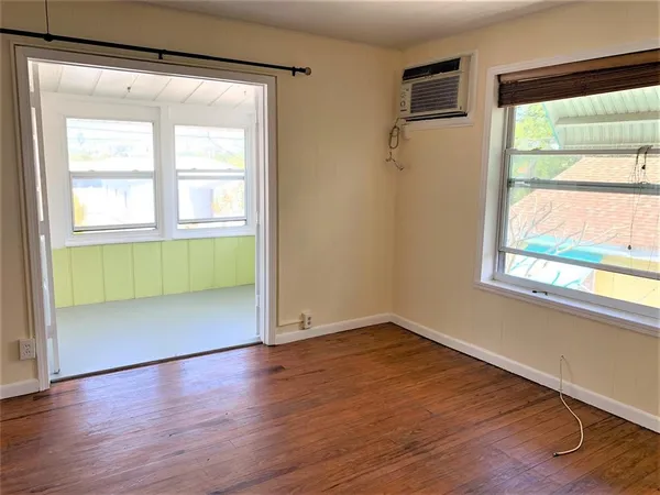 an empty room with wooden floor a ceiling fan and windows