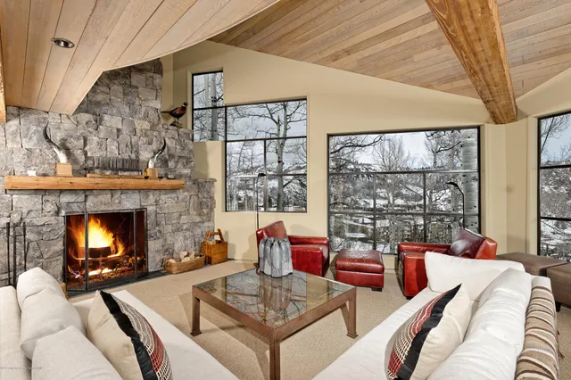 a living room with furniture a fireplace and large windows