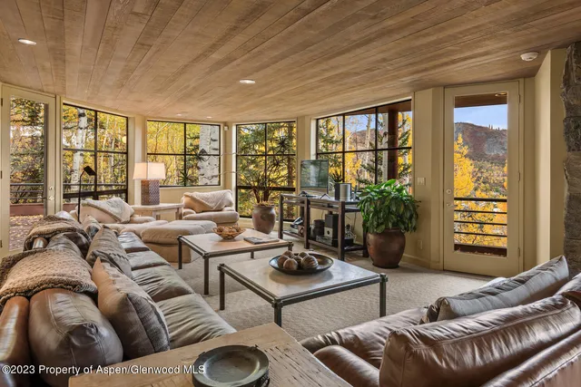 a living room with furniture a flat screen tv and a floor to ceiling window