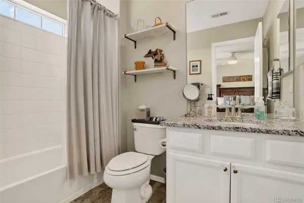a bathroom with a granite countertop sink a toilet and a mirror
