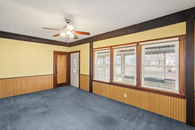 a view of an empty room with chandelier fan and fire place