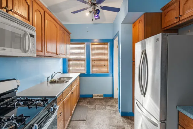 a kitchen with stainless steel appliances granite countertop a refrigerator a stove and a sink