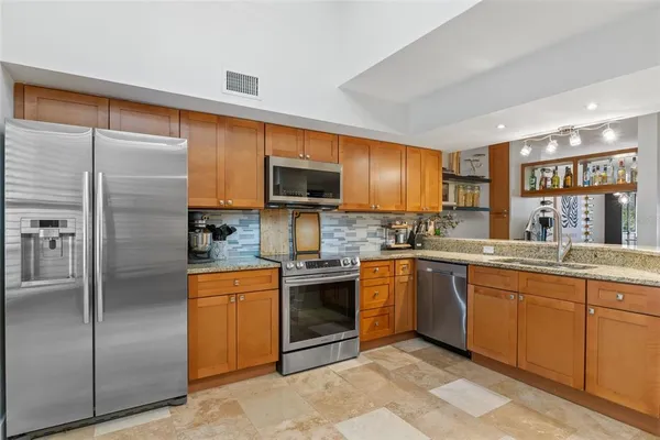 a kitchen with stainless steel appliances granite countertop a stove top oven a refrigerator and a sink