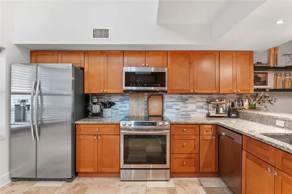 a kitchen with stainless steel appliances granite countertop a stove a sink and a microwave