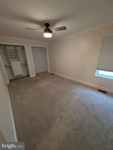 a view of an empty room and chandelier fan