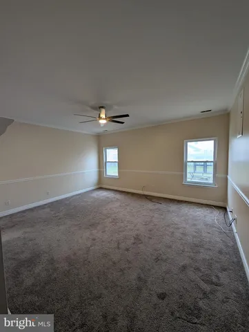 an empty room with windows and ceiling fan view