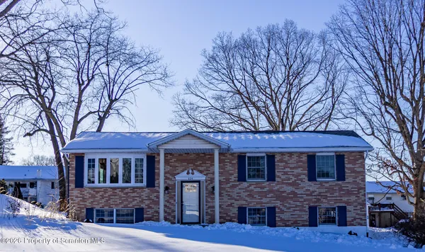 a front view of a house with a tree
