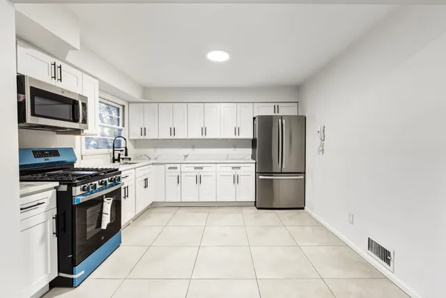 a kitchen with stainless steel appliances granite countertop a stove top oven a sink and a refrigerator