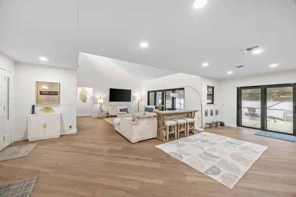 a large white room with kitchen island a flat screen tv a stove and a refrigerator
