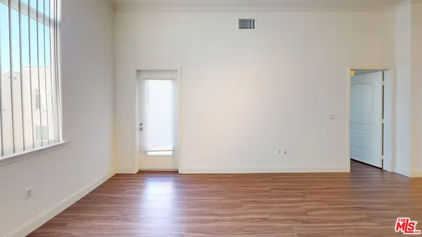 a view of an empty room with wooden floor and a window