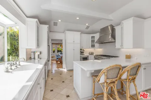 a kitchen with stainless steel appliances a stove a sink a refrigerator and a dining table with wooden floor