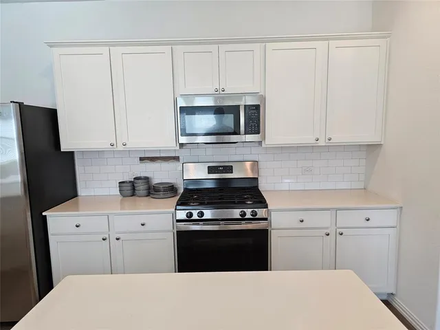 a kitchen with stainless steel appliances a stove a microwave a sink and cabinets