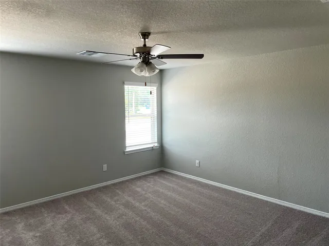 an empty room with a window and a fan