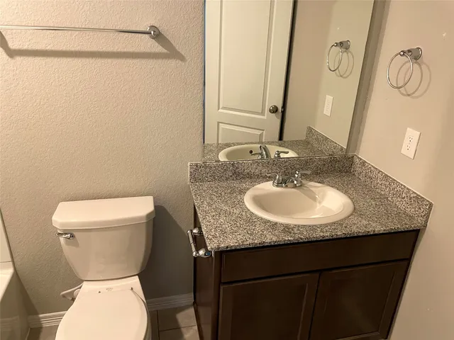 a bathroom with a granite countertop sink toilet and a mirror