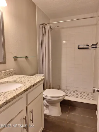 a bathroom with a granite countertop bathtub shower sink vanity and toilet