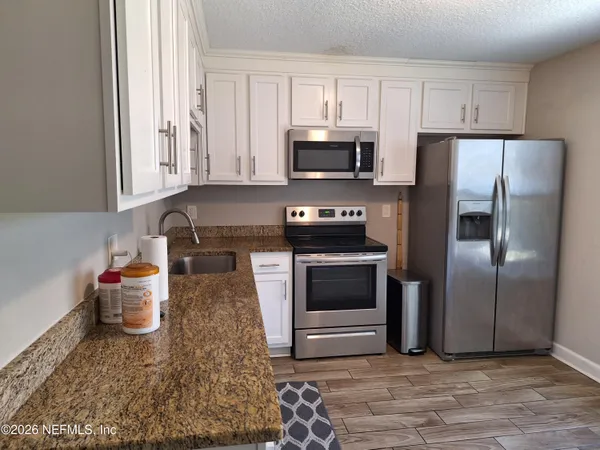 a kitchen with stainless steel appliances granite countertop a refrigerator sink and stove
