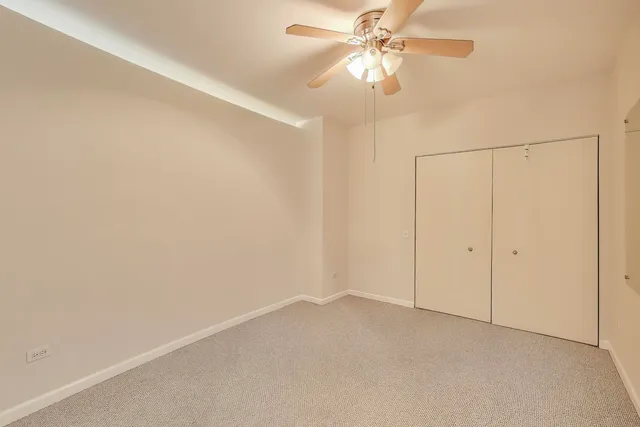 an empty room with a fan & a ceiling fan