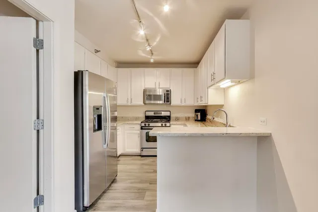 a kitchen with stainless steel appliances granite countertop a refrigerator a stove a sink dishwasher and a refrigerator with wooden floor