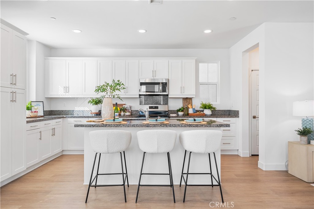 11016 Getaway Drive Rancho Cucamonga, CA 91730 - Photo 14 of 44 a kitchen with stainless steel appliances granite countertop a stove a sink a microwave a refrigerator and white cabinets