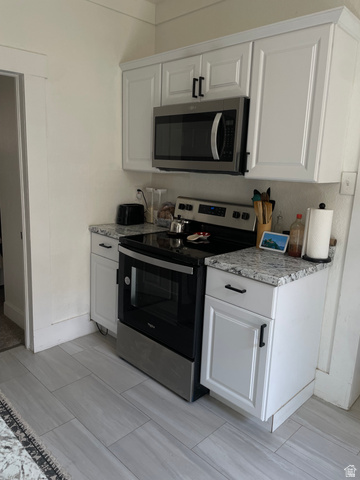 857 27th Street Ogden, UT 84403 - Photo 20 of 20 Kitchen area featuring white cabinetry with dark hardware, a stainless steel microwave, a stainless steel range, granite-style countertops, and light-toned tile flooring